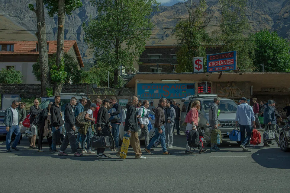 Young Russians line up for a bus to Tbilisi, in Stepantsminda, Georgia, a small town near the border crossing with Russia, Sept 29, 2022. A mountain pass into Georgia has become a choke point for Russians fleeing the country, many of them men who faced being drafted and sent to fight in Ukraine.