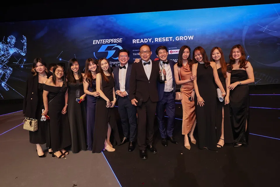 Business Edge founder and chief executive officer John Koh (holding award) with the company's director of operations Joel Koh (fifth from right) and other team members at the Enterprise 50 Awards in 2022, the year the company won an E50 award.