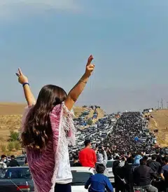An unveiled woman standing on top of a vehicle as thousands make their way towards a cemetery to mark 40 days since  Mahsa Amini’s death, defying heightened security measures as part of a bloody crackdown on women-led protests.