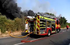 A firefighters truck is parked near a fire that burns during a heatwave, in Rainham, east London, Britain, July 19, 2022. 