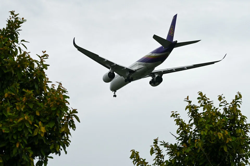 A Thai Airways passenger plane approaches for landing at Changi International Airport in Singapore on June 20, 2022. (Photo by Roslan RAHMAN / AFP)