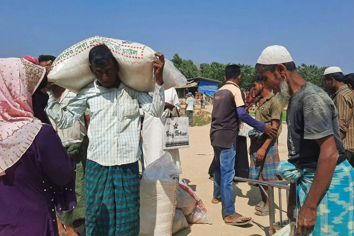 Rohingya refugees carrying relief supplies after collecting them in a refugee camp in Ukhia in Bangladesh on Mar 2.  A drastic fall in aid pledges last year left only US$553 million to meet their needs, well below the funds sought by aid agencies. 