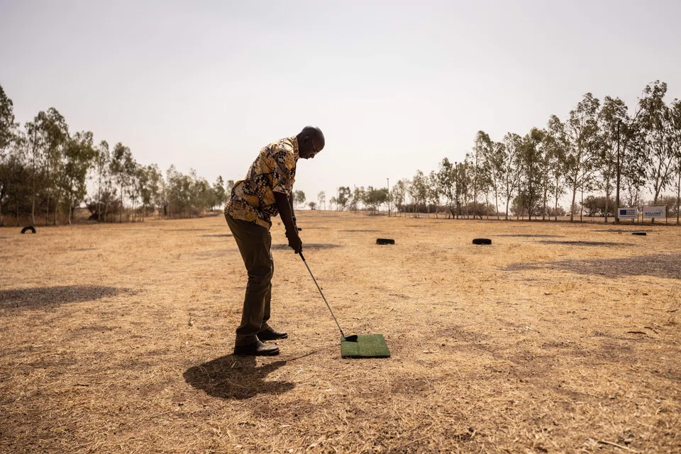 Salif Samake, president of Ouagadougou's Golf Club, tees off at one of the club's three courses. Here, the fairways comprise earth, stones and sinewy shrubs rather than manicured lawns.