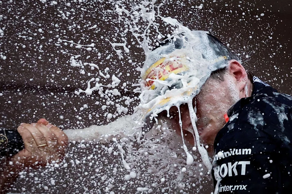 Red Bull's Max Verstappen celebrates with champagne on the podium after winning the Monaco Grand Prix.