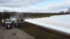 A load of corn is poured into a tractor with grain sleeves, temporary grain storage solution, in the village of Kozyn in Kyiv region, Ukraine, Nov 9, 2022.