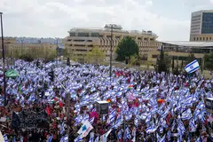 As lawmakers met in parliament, tens of thousands of protesters returned to the streets in Tel Aviv and Jerusalem, meanwhile, many waving the blue and white Israeli flags that have been become an emblem of the protests.