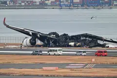Officials look at the burnt wreckage of a Japan Airlines passenger plane on the tarmac at Tokyo International Airport at Haneda, Tokyo on Jan 3, 2024, the morning after the JAL airliner hit a smaller coast guard plane on the ground. 