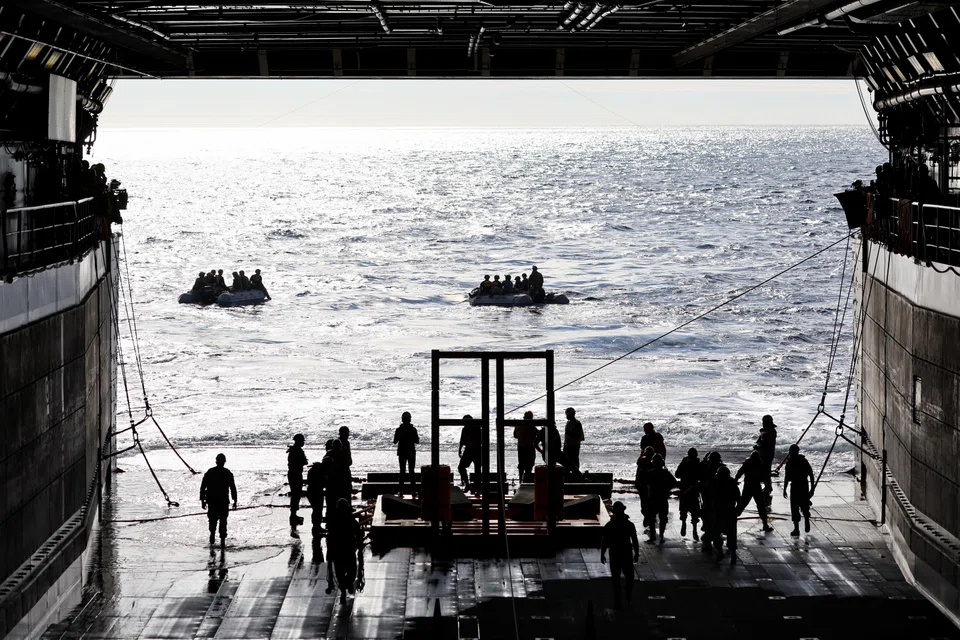 US Navy divers depart the U.S.S. Portland in small vessels as part of recovery operations before Nasa's Orion Capsule splashed down after a successful uncrewed mission.