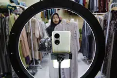 A sales promoter holds a dress as she live-streams on an e-commerce platform at a shop in Depok, Indonesia.