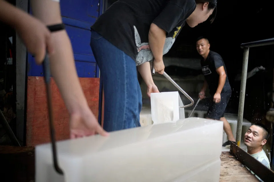 Employees move ice blocks onto a truck at Shanghai Yuhu ice-making factory, amid a heatwave warning in Shanghai, China July 26, 2022. 