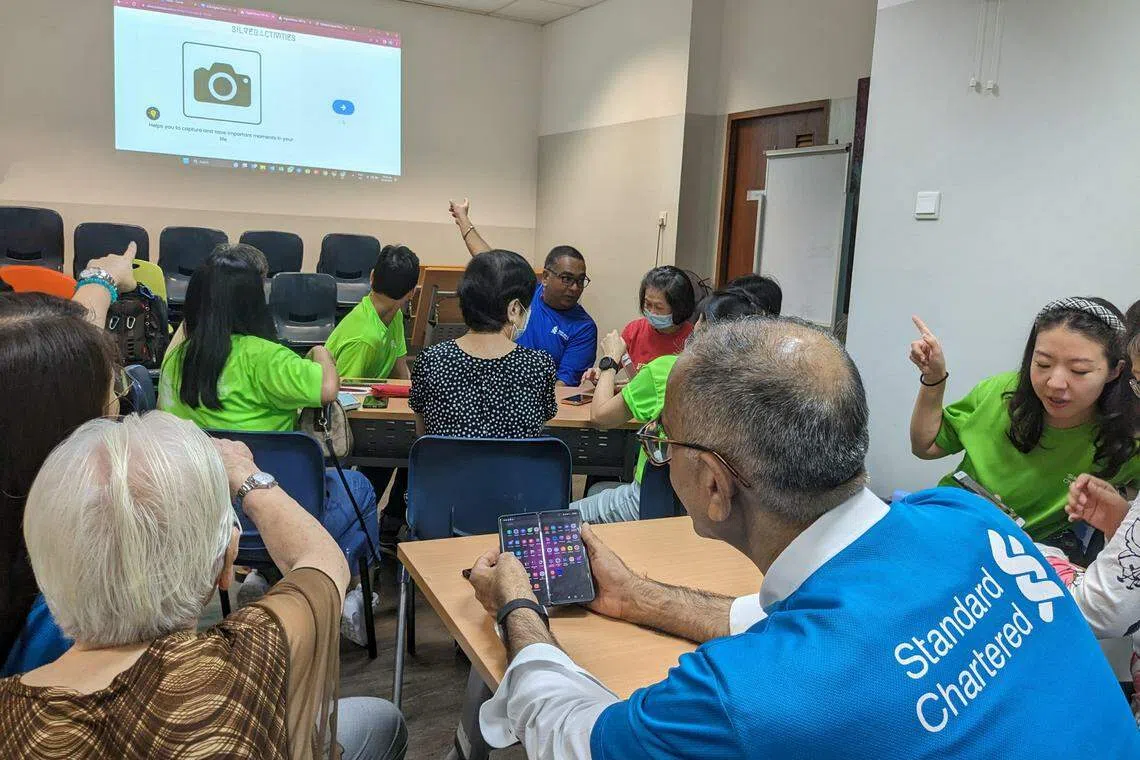 StanChart volunteers helping seniors with their smartphone queries at a digital clinic. The bank hopes to encourage more seniors to embrace technology.