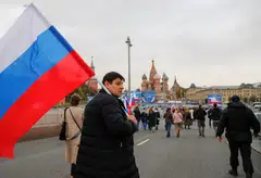 People approach screens located near the Kremlin and Red Square before the live broadcast of a ceremony to declare the annexation of the Russian-controlled territories of four Ukraine's Donetsk, Luhansk, Kherson and Zaporizhzhia regions.