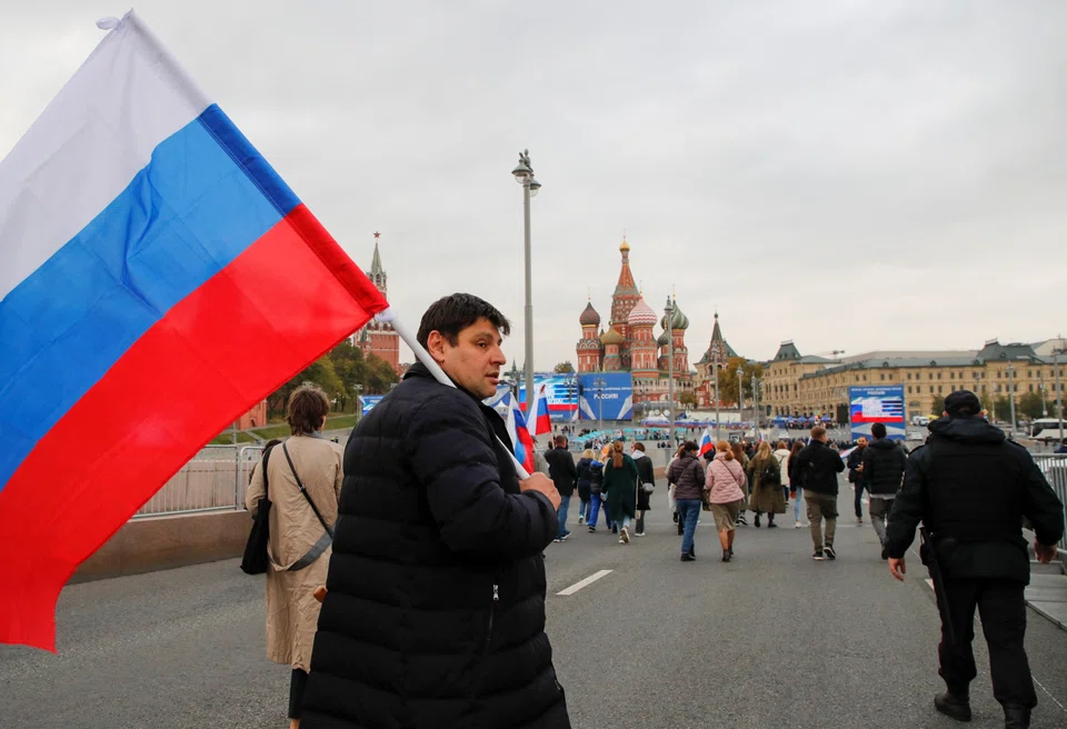 People approach screens located near the Kremlin and Red Square before the live broadcast of a ceremony to declare the annexation of the Russian-controlled territories of four Ukraine's Donetsk, Luhansk, Kherson and Zaporizhzhia regions.