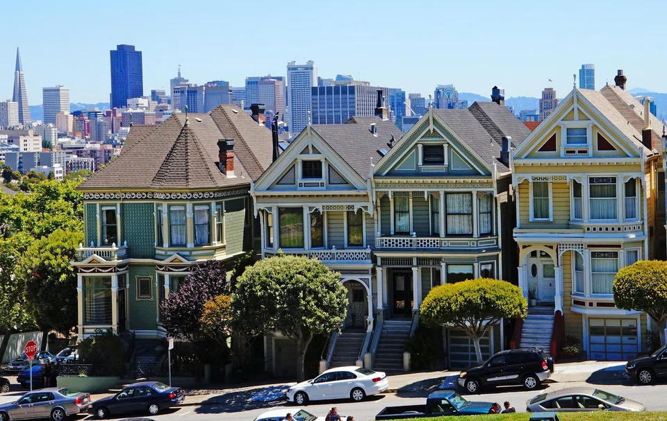 The famous Painted Ladies, which are Victorian-era houses, set against San Francisco's skyline of office and commercial buildings. 