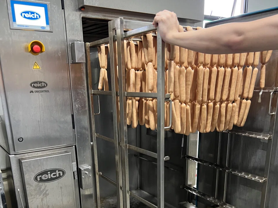 A fresh batch of sausages being pushed into a smokehouse for smoking and cooking.