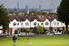 A person walks with a dog in front of a row of residential housing in south London, Britain, August 6, 2021. REUTERS/Henry Nicholls