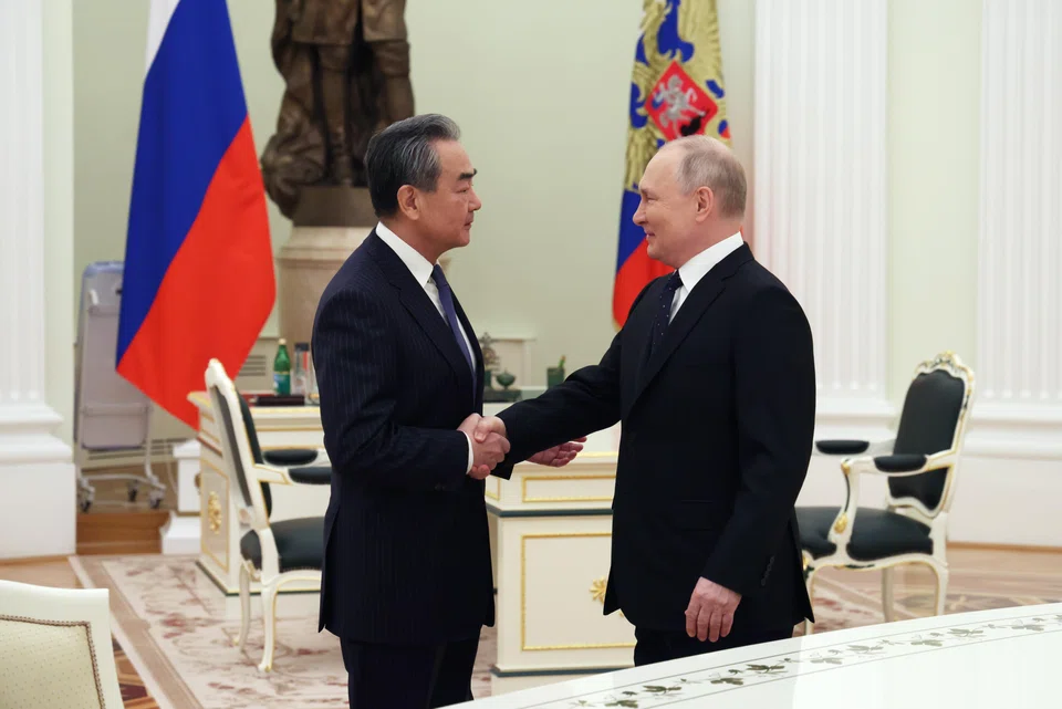 Russian President Vladimir Putin shakes hands with China's top diplomat Wang Yi during their meeting in the Kremlin on 22 Feb 2023. 