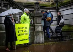 Climate activists hold a sign that reads "Schiphol stop polluting" as they protest outside a court where the aviation industry is instituting summary proceedings against the government over plans to limit flights at Amsterdam's Schiphol Airport for environmental reasons in Haarlem on March 21, 2023. 