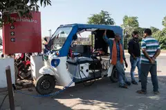 An electric rickshaw driver charges up at a Mahindra showroom in Darbhanga, India. Of all the changes the world is making to slow global warming, electric vehicle sales are the only category on track to meet climate goals. 