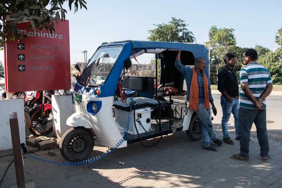 An electric rickshaw driver charges up at a Mahindra showroom in Darbhanga, India. Of all the changes the world is making to slow global warming, electric vehicle sales are the only category on track to meet climate goals. 