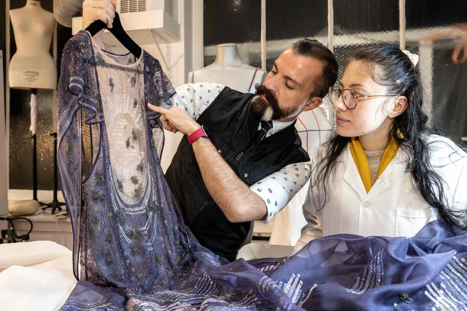 French fashion designer Julien Fournie (left) working on an embroidered dress at his studio