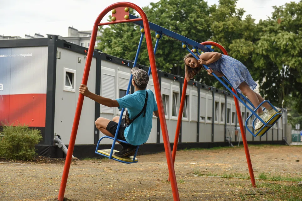 Children play on a swing outside trailers in Bucha city near Kyiv. Around 30-35 people live inside trailers set up as temporary homes for families who lost their houses. 