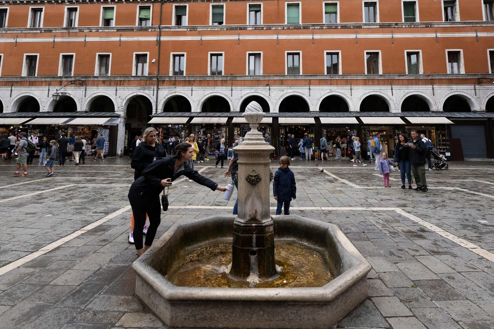 A tourist fills her water bottle at a fountain in Venice. Tourism contributes to the production of 28-40 per cent of the city's waste, showed local government data.