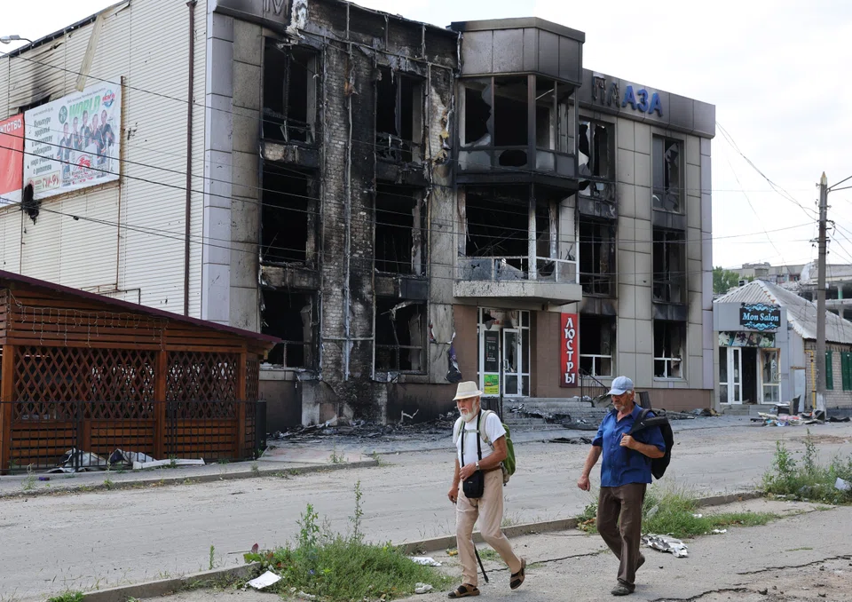 Local residents walk past a building destroyed during Ukraine-Russia conflict in the city of Lysychansk in the Luhansk Region, Ukraine July 4, 2022.