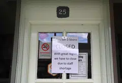 A sign on a restaurant door announcing its closure due to a lack of staff in Keswick in the Lake District, Britain, June 20, 2022.