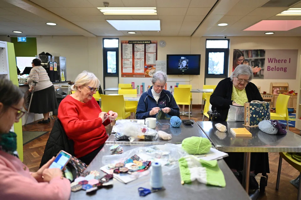 At Chantry Library, a group of women gather round a table to knit, while donated clothes hang next to the library’s entrance on “kindness racks”. 