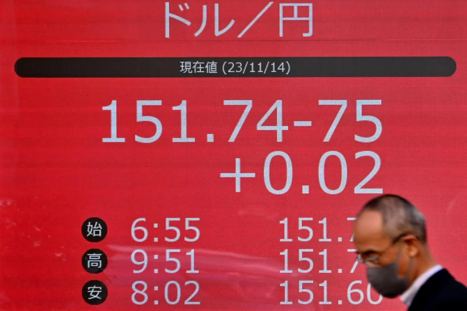 A man walks past an electronic board showing the rate of the Japanese yen versus the US dollar in Tokyo on Nov 14, 2023. The BOJ‘s ultra-loose monetary policy has drawn criticism from analysts and some politicians for causing sharp yen falls that boost import prices and the cost of living for households.