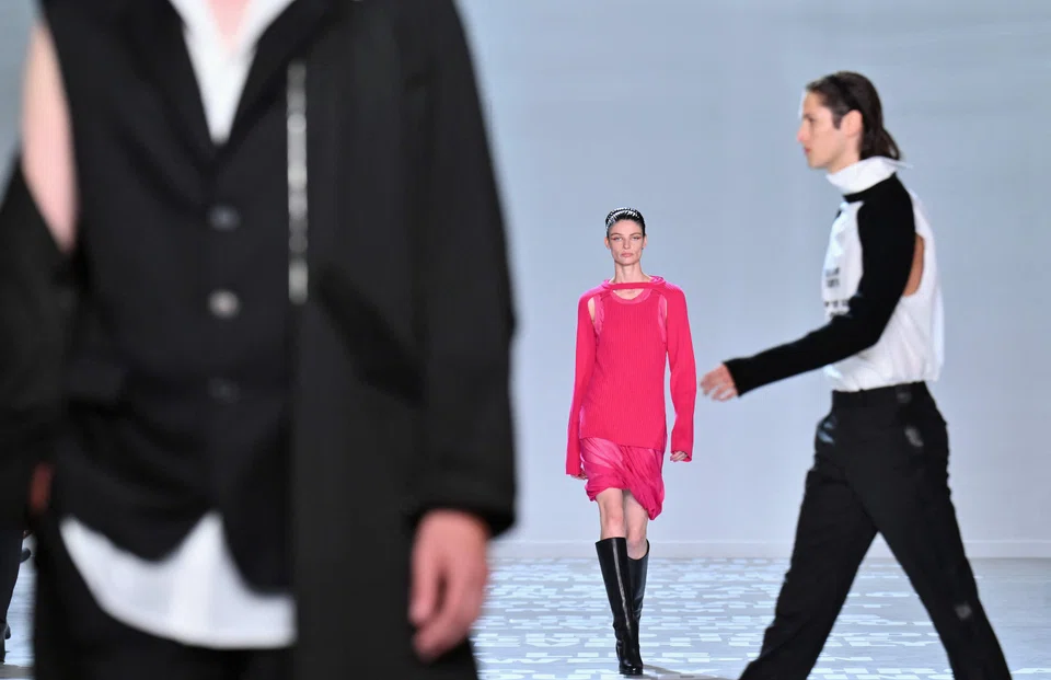 Designs by Helmut Lang during New York Fashion Week. The collection includes black jacket-trouser ensembles that are worn comfortably, but crossed by near-fluorescent pink or gold-coloured stripes down the legs, on the belt and the shoulder strap.