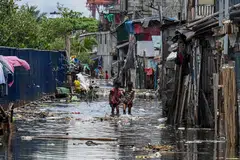 Children walk through a flooded area due to high tide in Baseco, one of the biggest slums in Manila on Aug 15, 2022. The Vulnerable Group of Twenty (V20) – a group of 55 economies exposed to the fallout from climate change – expect debt service payments to rise to US$69 billion by 2024.
