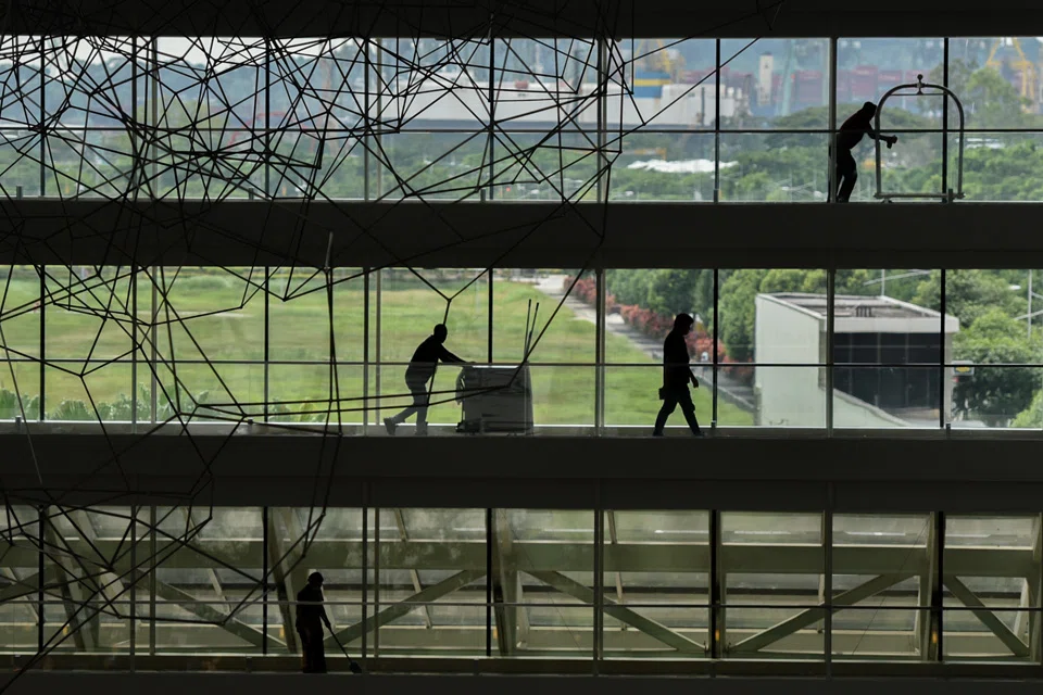 Hotel staff, including a cleaner and a bellman walk past at the Marina Bay Sands Hotel.