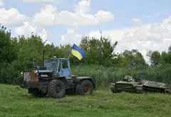 A farm tractor tows an armoured personnel carrier, abandoned by Russian troops and commandeered by a Ukrainian farmer at the end of March, during an event dedicated to the release of the latest military-themed stamps issued by Ukraine's national postal service.