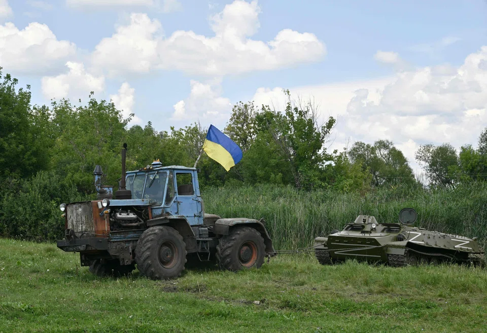 A farm tractor tows an armoured personnel carrier, abandoned by Russian troops and commandeered by a Ukrainian farmer at the end of March, during an event dedicated to the release of the latest military-themed stamps issued by Ukraine's national postal service.