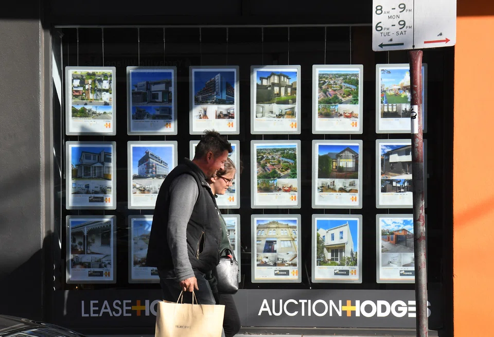 A real estate agent's window advertising houses for sale and auction in Melbourne, where prices fell 8.5 per cent this year.  