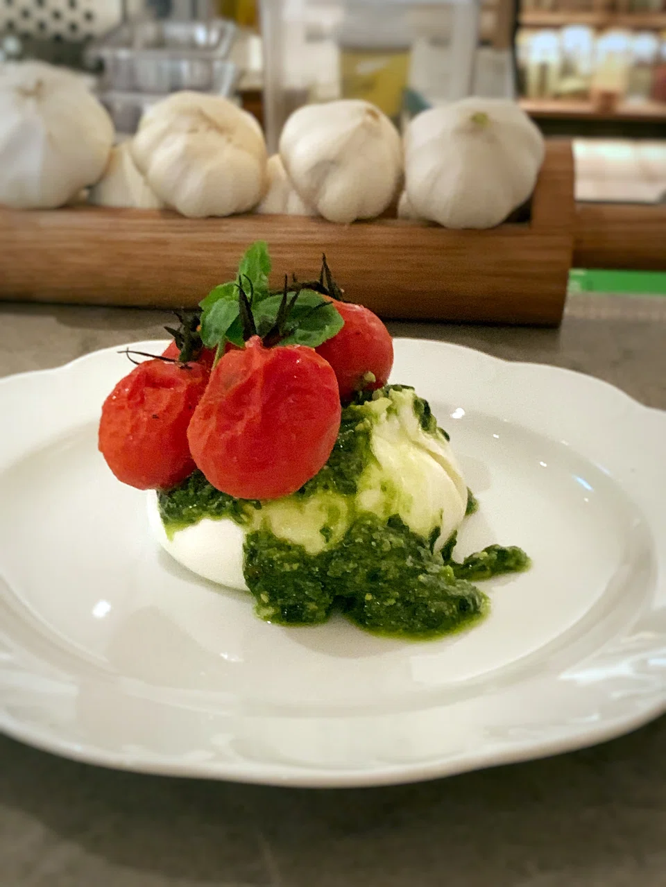 The Mozza Caprese, simplicity on a plate, features burrata, pesto and cherry tomatoes.