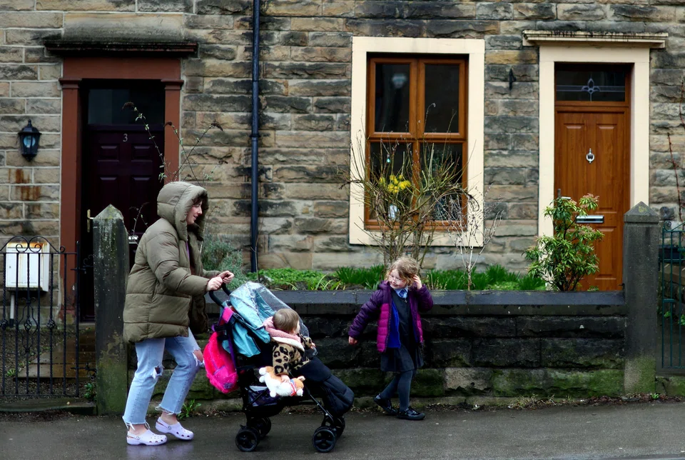 Louise Sharples, 35, walks with her daughters, Lola, 4 and Sunnie, 1, along a residential street in Clitheroe, East Lancashire, Britain, March 1, 2023. REUTERS/Hannah McKay