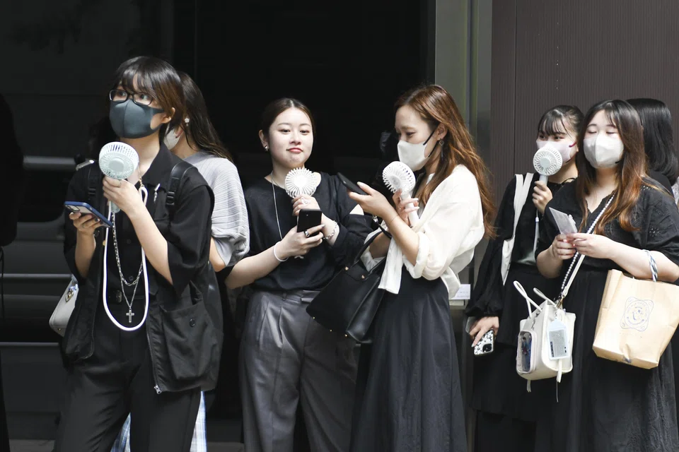 Women cool down with portable electric fans in the Yurakucho district of Tokyo, Japan, Sept 12, 2023.  