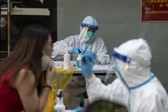 Healthcare workers in protective gear give residents their Covid-19 tests in Shanghai, China, on Sunday, July 10, 2022. Nearly 250 million people in China are now under some kind of virus control measures - more than double last week’s number - Japanese bank Nomura said on Monday.