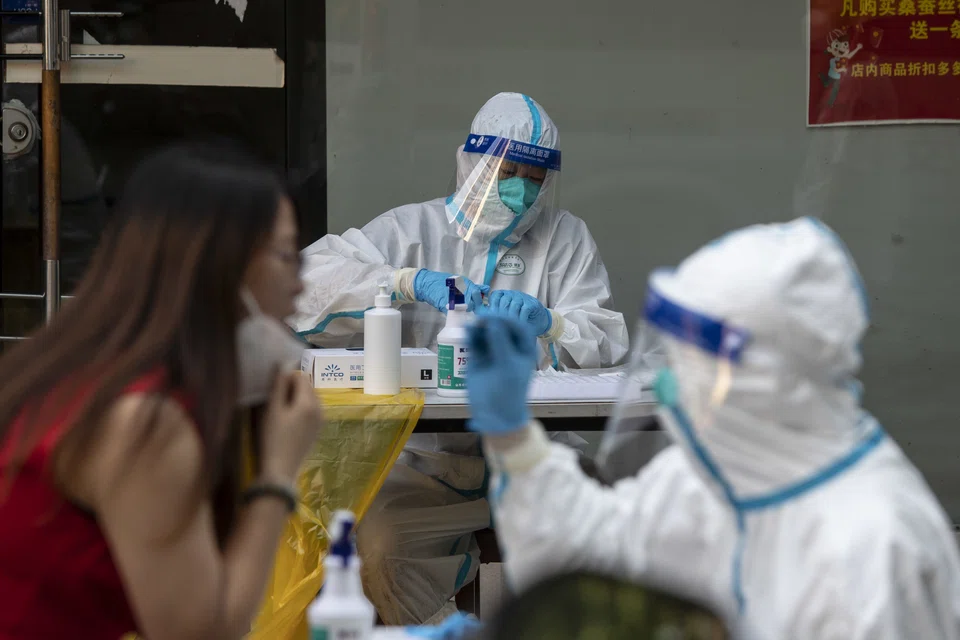 Healthcare workers in protective gear give residents their Covid-19 tests in Shanghai, China, on Sunday, July 10, 2022. Nearly 250 million people in China are now under some kind of virus control measures - more than double last week’s number - Japanese bank Nomura said on Monday.
