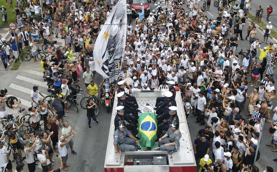 A fire engine carrying the body of Pele leads the funeral procession through the city of Santos before ending in a private burial.
