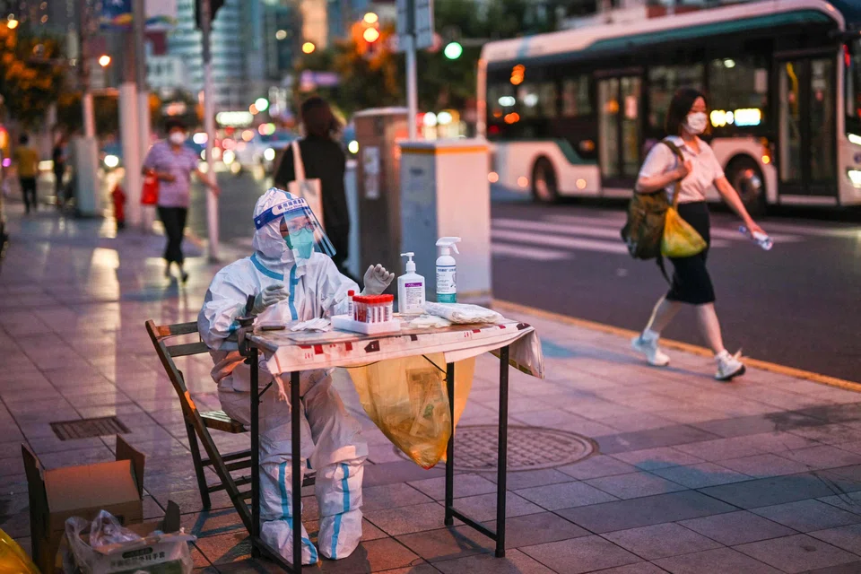 A health worker waits to test people for the Covid-19 coronavirus on a street next to a residential area in the Jing'an district of Shanghai on July 5, 2022. 