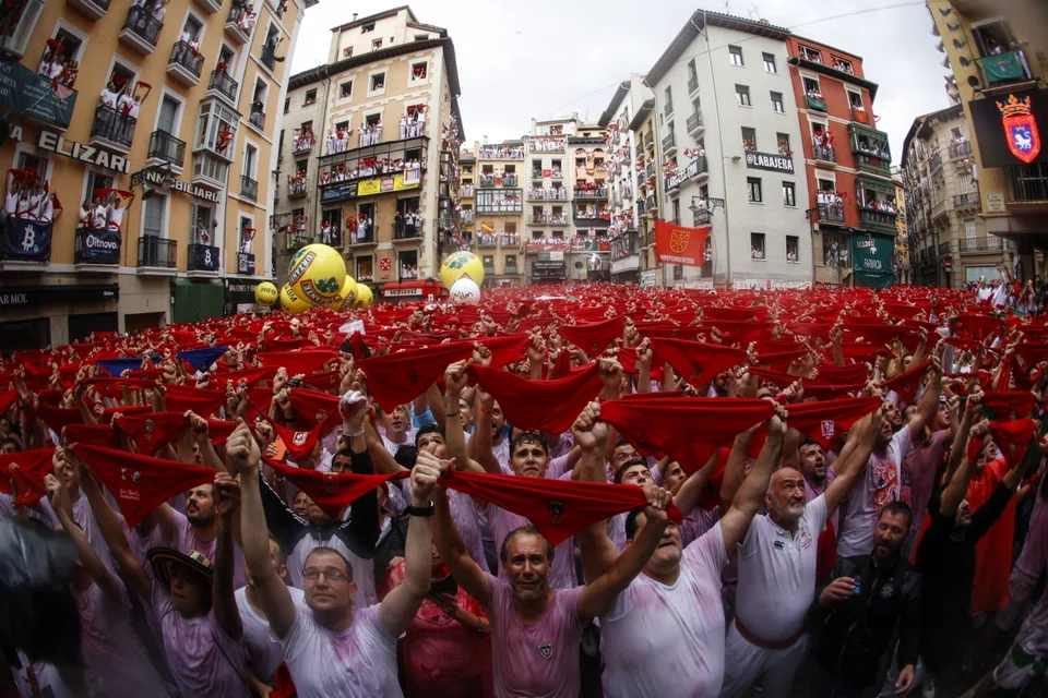 Thousands of party-goers from around the world - most dressed in the traditional all-white outfit with a red scarf - responded ecstatically, screaming "Viva San Fermin!"