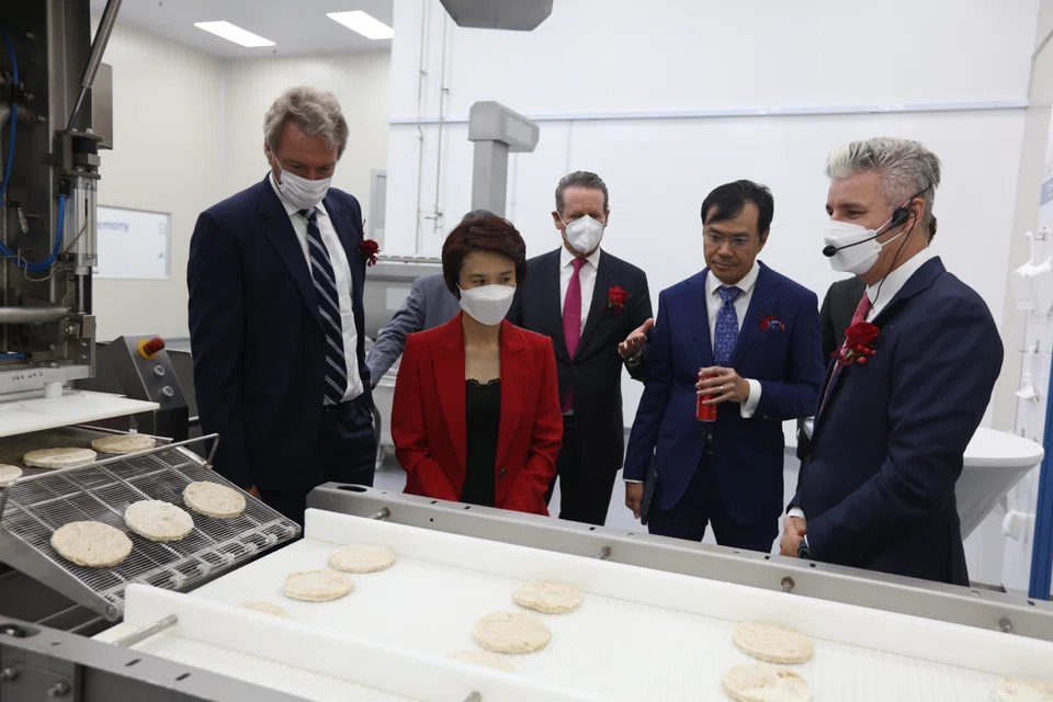 Watching the high-moisture extrusion-production processes at the Cremer Sustainable Foods' Tuas production facility on Wednesday (Jul 20) were, from left,  ASF chief executive Mathys Boeren, Minister of State for Trade and Industry Low Yen Ling, Cremer Group chairman Claus Georg Nette, EDB executive vice-president Damian Chan and Cremer's general manager for Sustainable Nutrition Damian Kruger.  