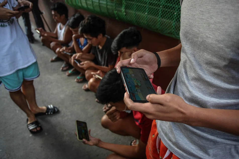 Young people engrossed playing a game on their mobile phones in suburban Manila. Eventually, when they are discarded for newer models or stashed away, the valuable gold, copper and other metals they contain will be hoarded, dumped or incinerated, causing health and environmental harm. 