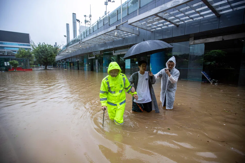 People wade through flood waters at the Shenzhen Bus Station in Shenzhen, in China's Guangdong province on Sept 8, 2023, after the city recorded the heaviest rains since records began in 1952. 