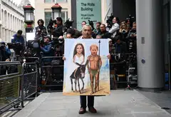 Political satire artist Kaya Mar holds his painting showing Prince Harry and Meghan Markle, ahead of the prince's arrival at the High Court in London.