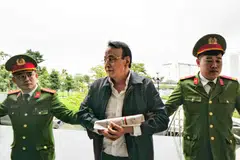 Chairman of Tan Hoang Minh group Do Anh Dung (centre) is escorted by police officers to a court for his trial on fraud charges in Hanoi on March 19, 2024.
